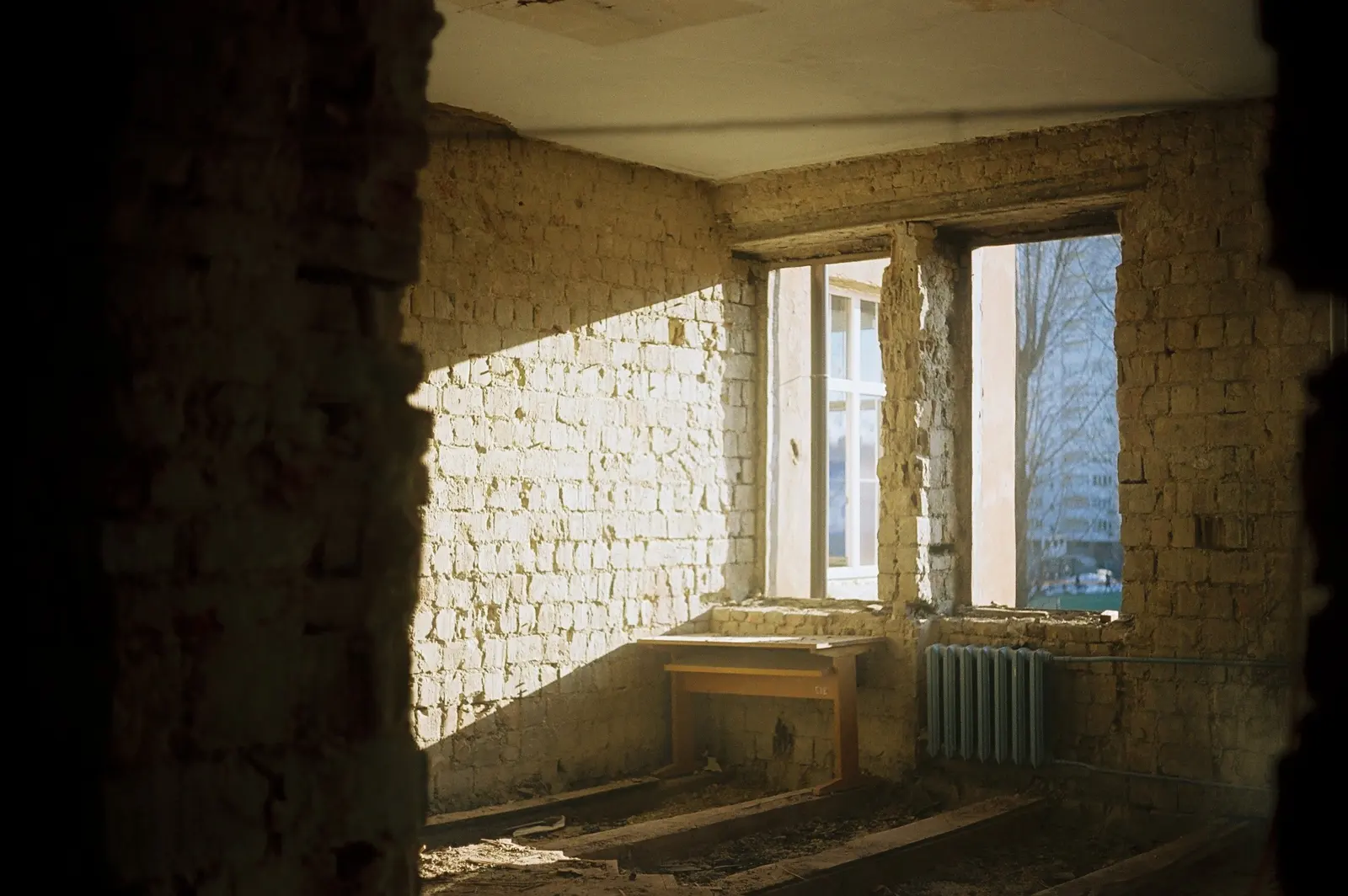 Une pièce à rénover, murs de briques mis à nu, le soleil entre par deux fenêtres.