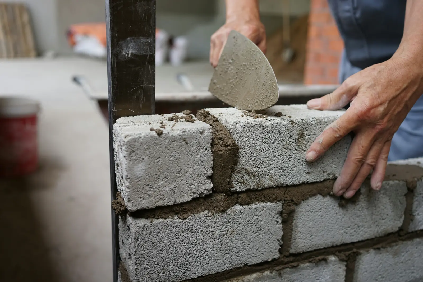 Des blocs de béton montés au mortier, la truelle à la main.