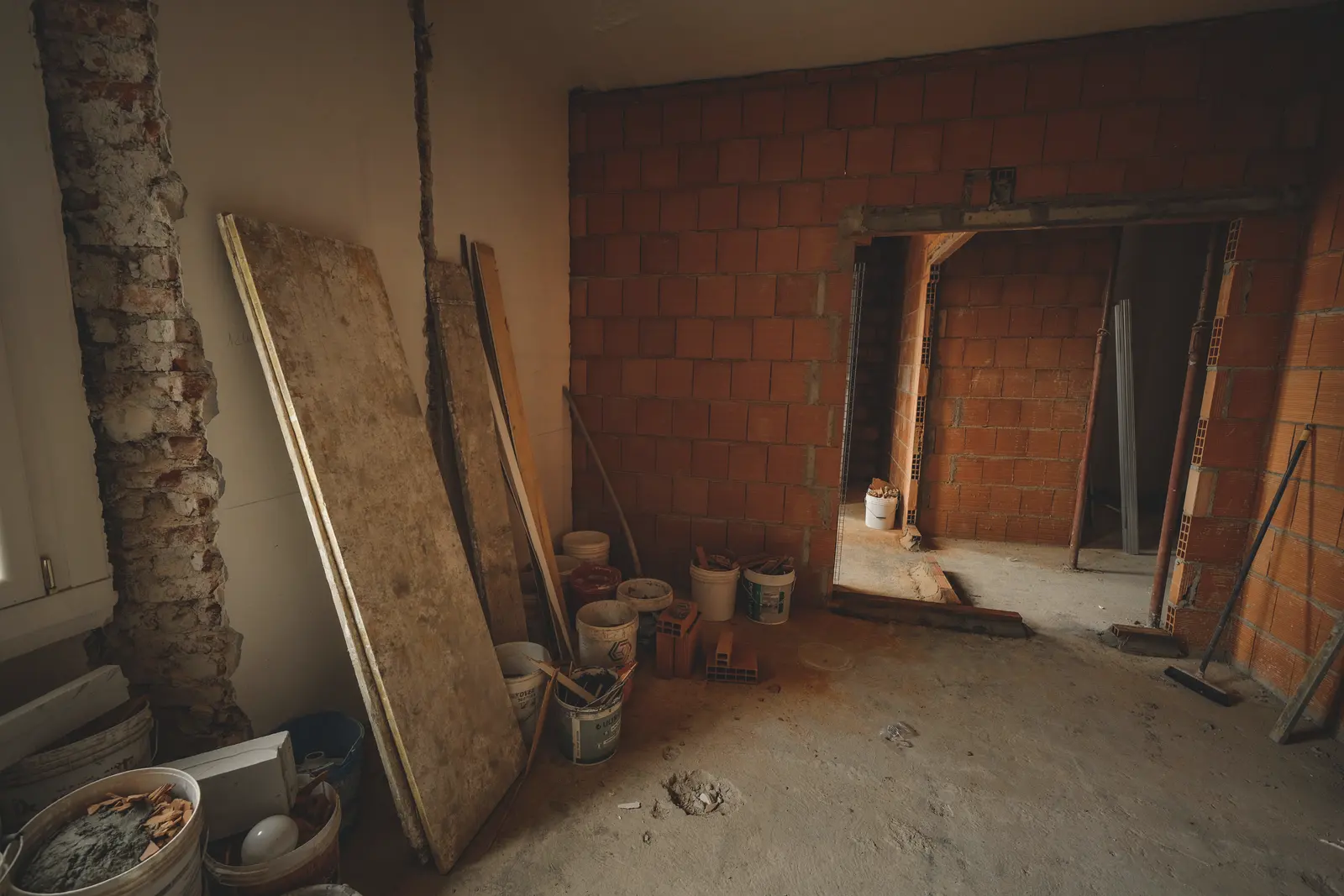 Un appartement en travaux : une cloison de briques neuve, les murs repris, les matériaux à pied d’œuvre.