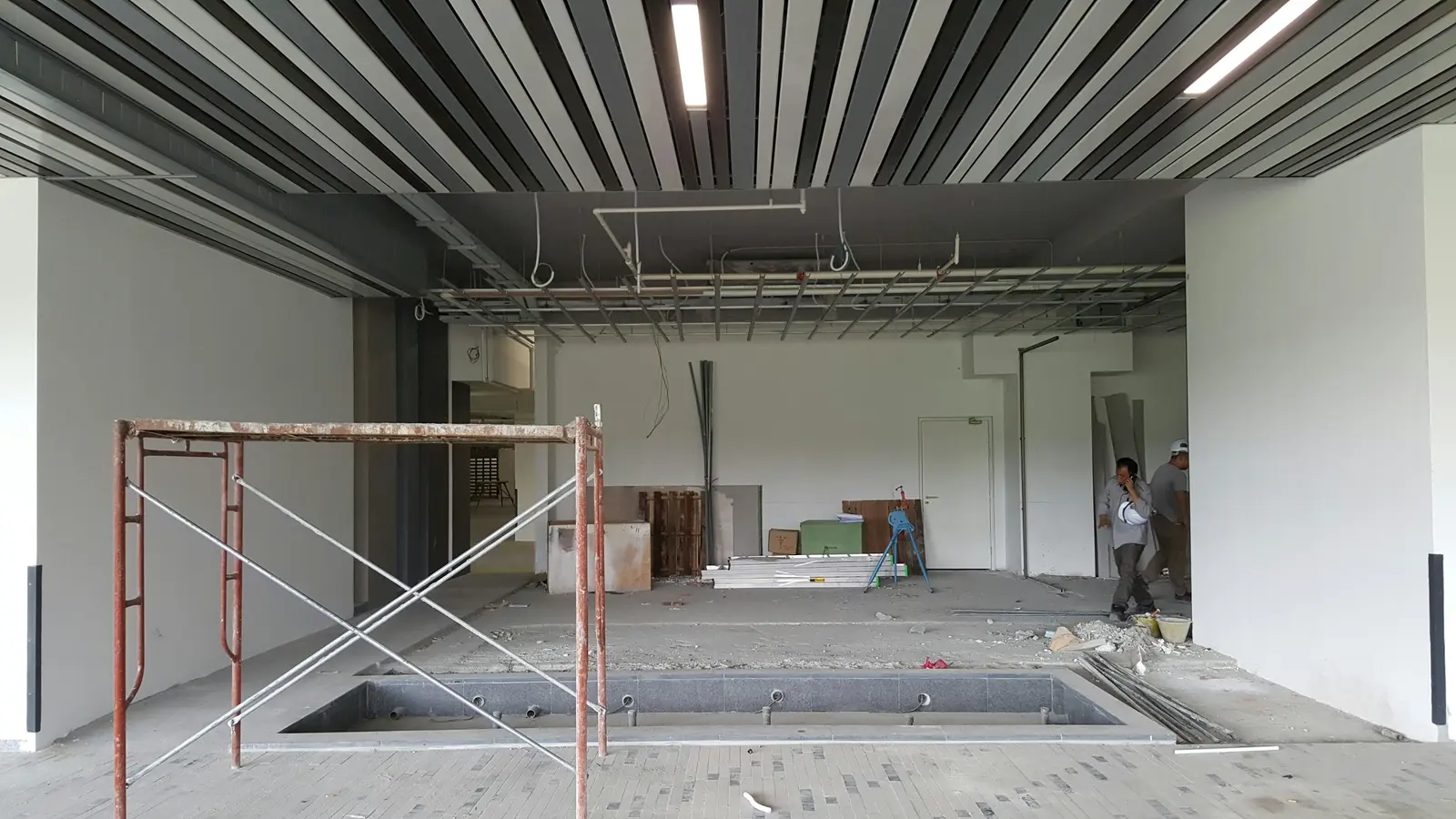Un plateau de bureaux en travaux : faux plafond ouvert, échafaudage roulant.